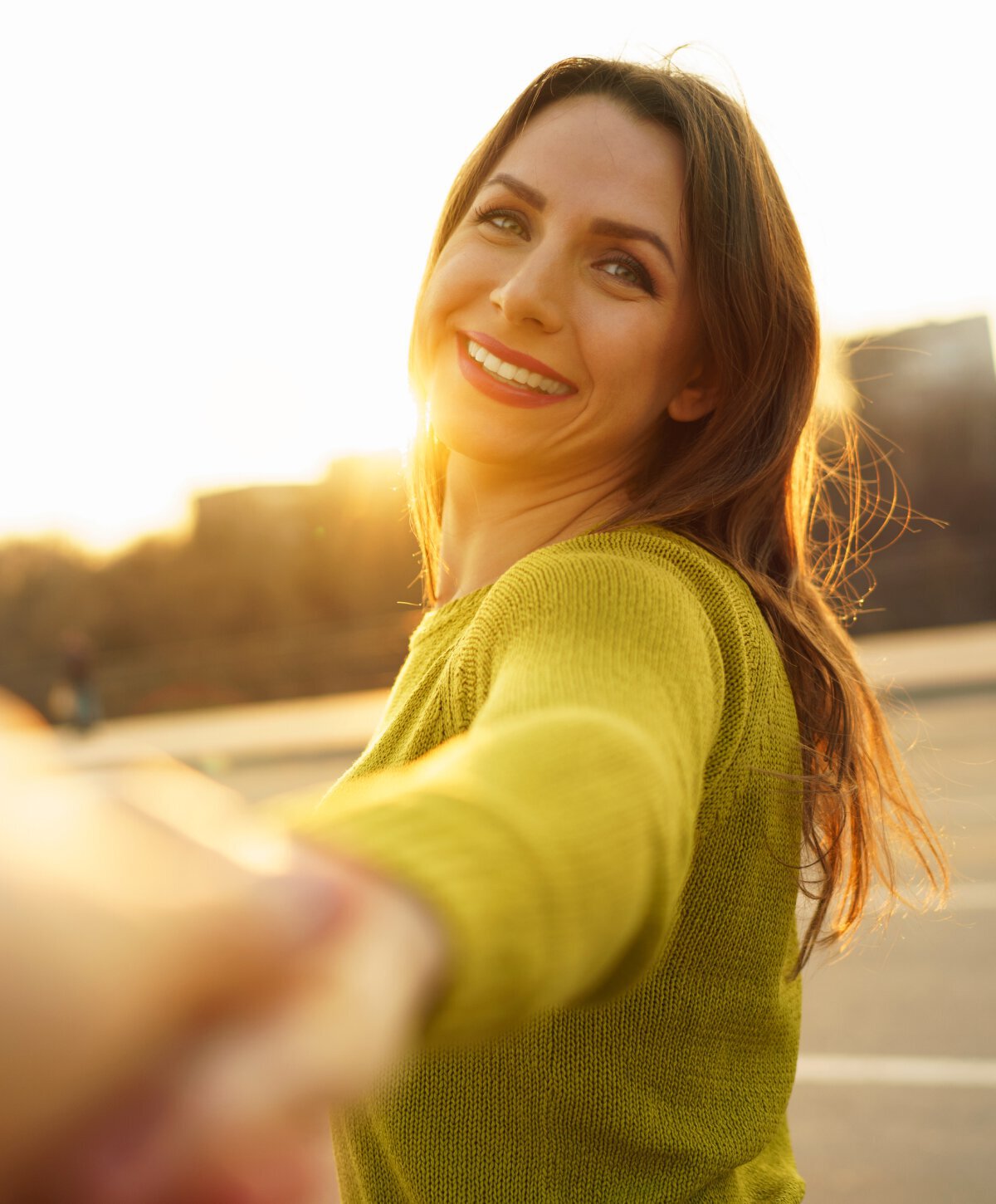 houston liquid facelift model smiling while reaching towards camera at sunset